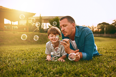 father and son blowing bubbles outside