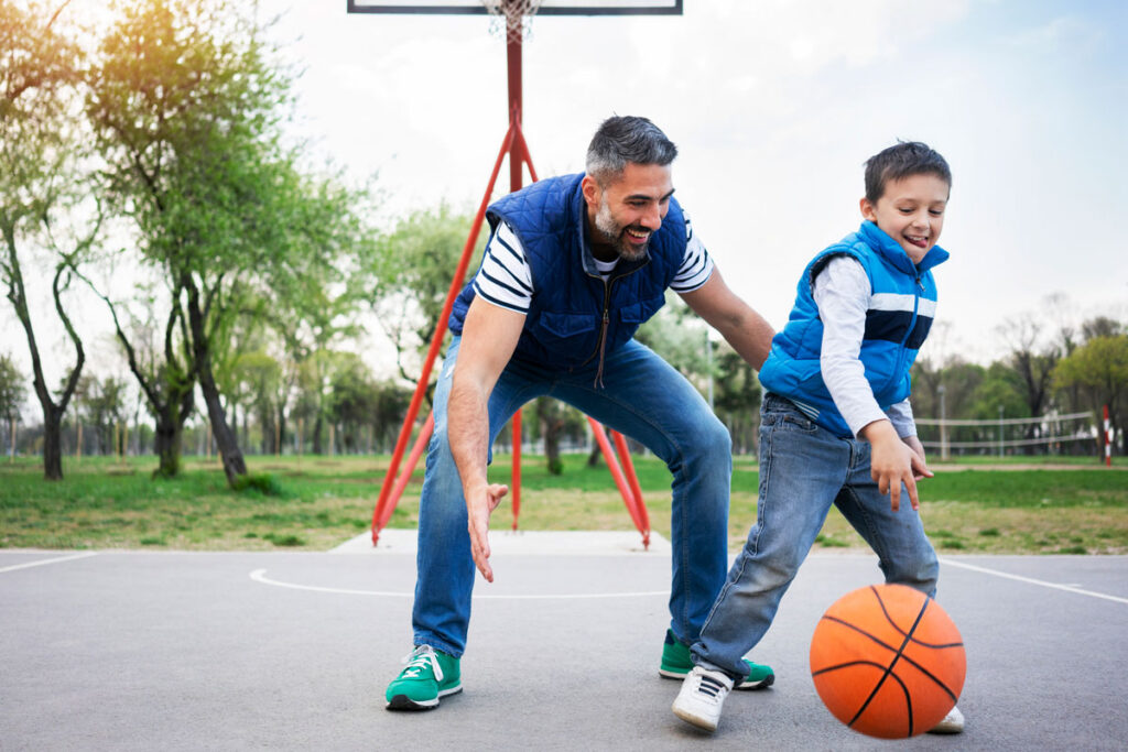 father son playing basketball at a park court